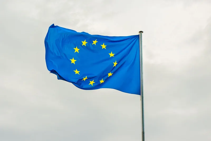 The European Union flag on a flagpole against a cloudy sky