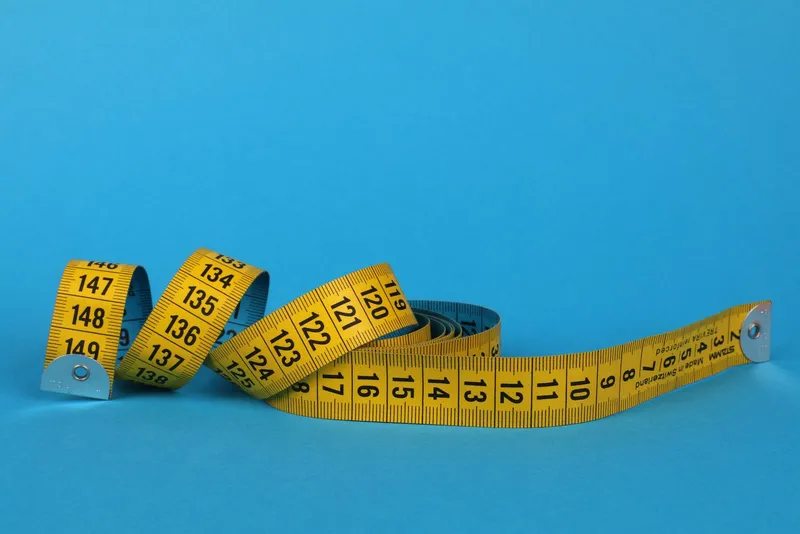 A coiled yellow measuring tape on a blue background