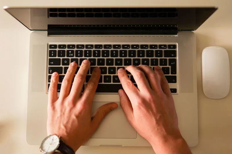 Hands typing on a laptop keyboard