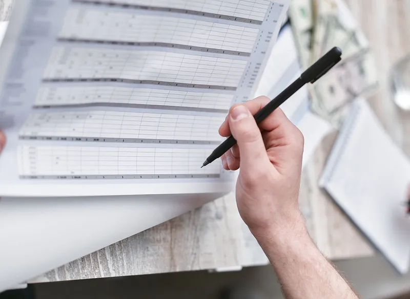 A person with a pen reviewing a financial document