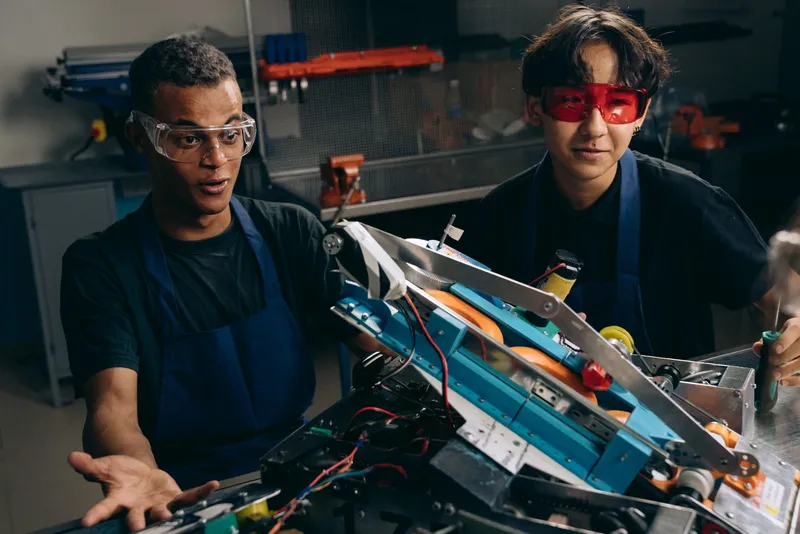 Two engineers in goggles working on a robotics prototype in a workshop